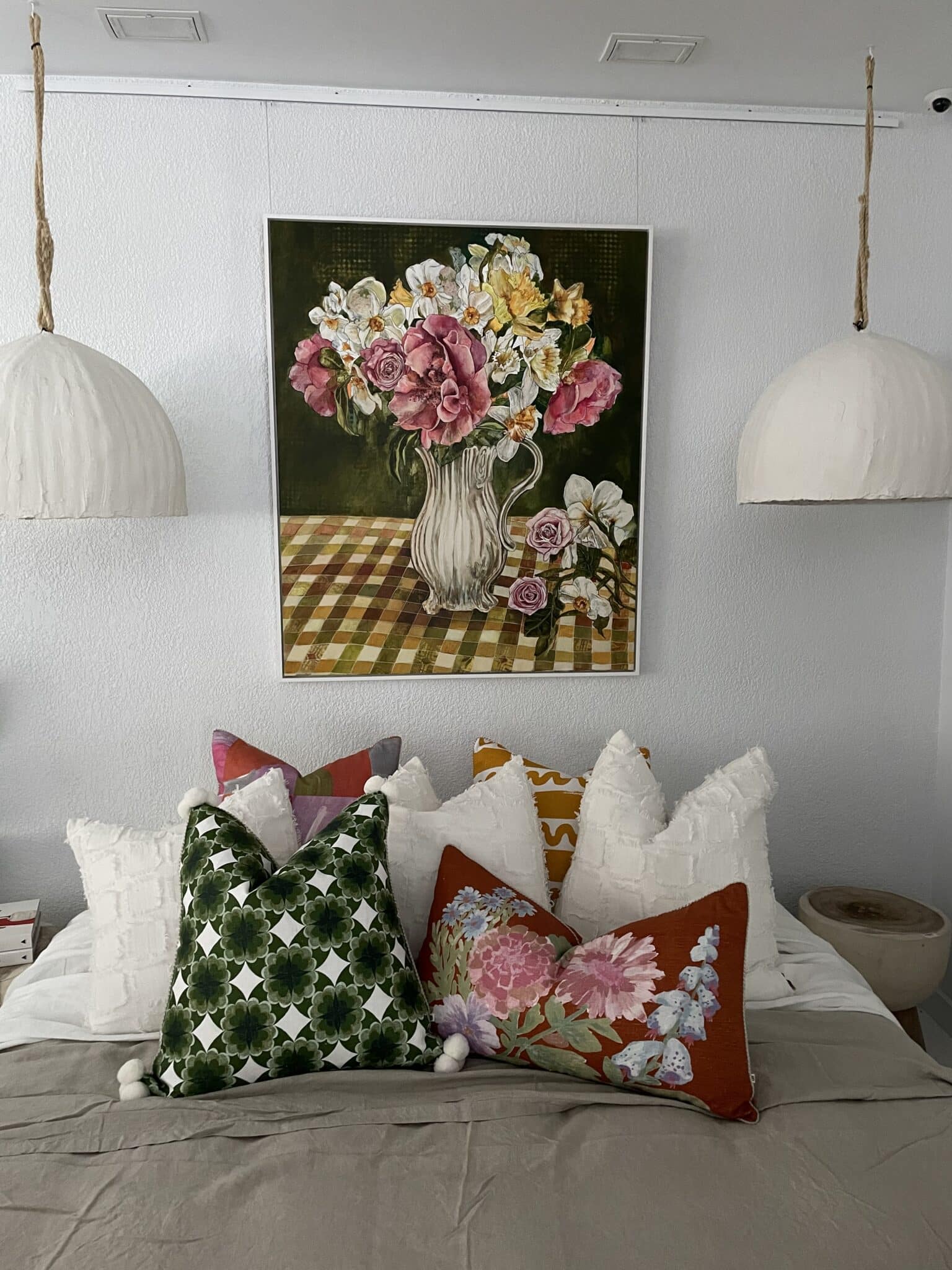 A floral artwork displayed above a bed in a bedroom